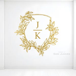 May include: Gold-colored wall decal featuring a laurel wreath design with the initials "J" and "K" inside a shield shape. The words "PROPERTY OF SIGN JUNKIES" are printed in the lower right corner.