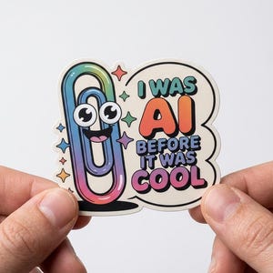 May include: A sticker featuring a cartoon paperclip with a rainbow gradient color scheme and googly eyes. The sticker has the text "I WAS AI BEFORE IT WAS COOL" in a bubble design with star accents.
