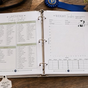 May include: A white three-ring binder open to two pages featuring a Livestock Packing Checklist with columns for sheep, goat, and swine supplies, and a Weight Tracker page with a grid graph and space for animal information, including small line art illustrations.