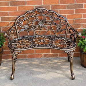 May include: A metal garden bench featuring a bronze-toned finish with black highlights. The backrest displays a floral rose motif with scrolling vines, while the seat and legs are decorated with intricate circular and floral patterns.