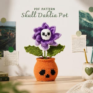 May include: A crocheted Skull Dahlia Pot with a purple flower and a skull center. The orange pot has black skull accents. Green leaves and a stem support the flower. The words "PDF PATTERN" and "Skull Dahlia Pot" are at the top.