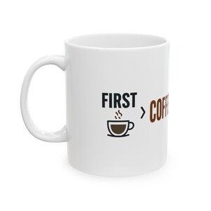 Könnte beinhalten: Ein weißer Keramikbecher mit dem schwarzen Text FIRST, einer kleinen Grafik einer dampfenden Kaffeetasse, einem Größer-als-Zeichen und dem braunen Text COFFEE. Das Design ist auf der Seite des Bechers gedruckt, der einen geschwungenen Henkel links hat.