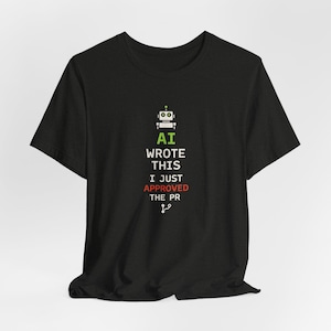 Op de afbeelding: Een zwart t-shirt met korte mouwen voorzien van een afbeelding van een kleine robot boven de tekst AI WROTE THIS I JUST APPROVED THE PR in het wit, met het woord APPROVED in het rood, een groen stipje boven de robot en een vertakkingsicoon.