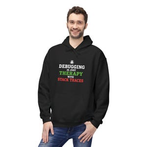 May include: A black hooded sweatshirt featuring a small white bug icon above the text "DEBUGGING IS JUST THERAPY WITH STACK TRACES". The word "DEBUGGING" is in white, "THERAPY" is in green, and "STACK TRACES" is in red, centered on the chest.