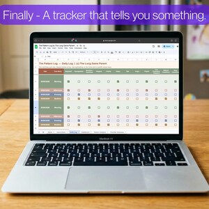 May include: A silver MacBook Air laptop displaying a spreadsheet titled "The Pattern Log - Daily Log" on a wooden table. The screen shows a grid with checkboxes. A white mug with coffee sits to the right. Text above the screen reads "Finally - A tracker that tells you something."