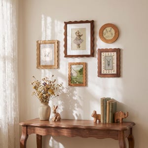 May include: A wooden console table with a scalloped edge holds a ceramic vase of dried flowers, a ceramic rabbit figurine, a stack of books, and two wooden animal carvings. Five framed pictures hang on the wall, featuring illustrations of animals.