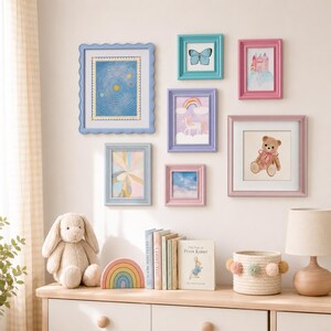 May include: A gallery wall arrangement featuring seven colourful picture frames containing illustrations of a solar system, a butterfly, a castle, a unicorn with a rainbow, a teddy bear, and clouds, displayed above a shelf with a plush rabbit and books.