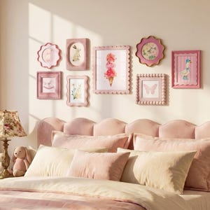 Puede incluir: Una composición de pared de galería con ocho marcos en tonos rosados de diversas formas y texturas, incluyendo diseños festoneados, con cuentas y rectangulares, que muestran ilustraciones de conejos, una mariposa, un pato y un helado.