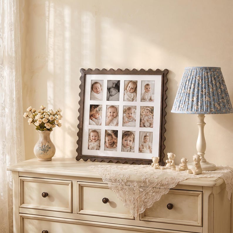 May include: A square dark wood picture frame with a scalloped edge containing a white mat with twelve rectangular openings displaying black and white photographs of infants. The frame is positioned on a light-colored wooden dresser surface.