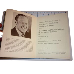May include: An open booklet with text and a black and white portrait of Gerald R. Ford. The text announces the 1977 Annual Membership Meeting and Dinner of the Convention and Visitors Bureau of Denver and Colorado.