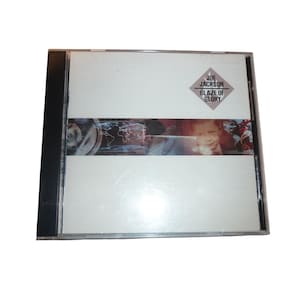 Puede incluir: Una caja de CD con una cubierta blanca. La cubierta presenta un logotipo en forma de diamante que dice "JOE JACKSON BLAZE OF GLORY". Una banda horizontal en el centro muestra un mapa del mundo y la cara de un niño. La caja tiene un lomo negro.