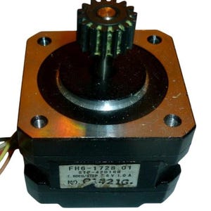 Puede incluir: Un motor paso a paso negro con una placa superior metálica y un engranaje central. Una etiqueta blanca en el lateral muestra el texto FH6-1728 01, STP-42D168, 1.8DEG/STEP, 6V, 1.0A y NO. 01421G. Varios cables finos multicolores sobresalen del lateral.