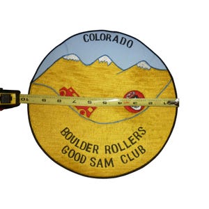 Può includere: Toppa rotonda ricamata con un paesaggio montano del Colorado, con la scritta "COLORADO" in alto e "BOULDER ROLLERS GOOD SAM CLUB" in basso. La toppa misura circa 23 cm di diametro.