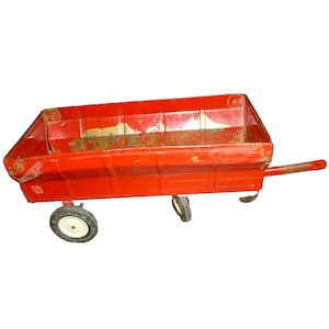 May include: A vintage red metal toy wagon with a rectangular bed and a long handle. The wagon has four small wheels with white tires and shows signs of wear and tear.
