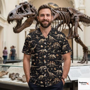 May include: A black short-sleeved button-down shirt featuring an all-over print of beige dinosaur skeletons, fossils, and ammonites. The shirt has a classic collar, a front button placket, and a straight hem, showcasing various prehistoric creatures.