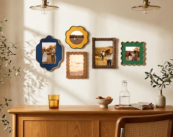 May include: A collection of five wall-mounted picture frames in various shapes and colors, including a large blue quatrefoil frame, a yellow scalloped circle, a brown beaded rectangle, a wavy-edged brown frame, and a green scalloped square.