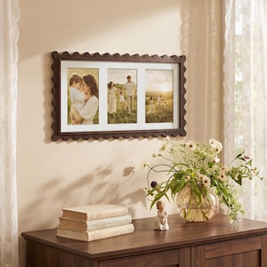 May include: A rectangular dark brown wooden picture frame with a scalloped edge design, featuring three vertical photo openings. The frame holds three separate photographs depicting family scenes in a grassy field during the golden hour.