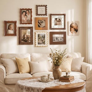 May include: A gallery wall arrangement featuring nine assorted rectangular and square picture frames in wood, white, and brown finishes, displaying various family photographs and text, positioned above a beige sofa with decorative pillows.