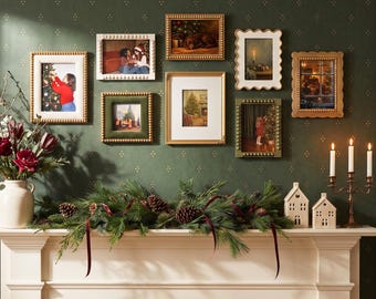 May include: A gallery wall arrangement featuring seven assorted rectangular picture frames in gold, white, and green finishes, displayed above a white fireplace mantel decorated with a pine garland, two ceramic houses, and a candle holder.