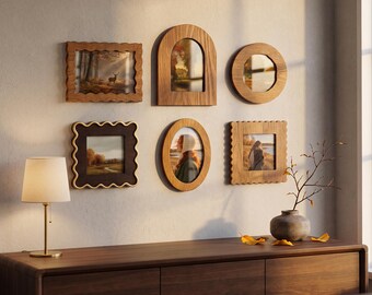 May include: A collection of six wall-mounted picture frames in various shapes including rectangular, arched, circular, and oval designs. The frames feature wooden textures and wavy edges, displaying landscape and portrait photographs on a neutral wall.