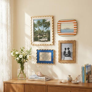 May include: Four wall-mounted picture frames with distinct designs: a large cream wavy frame, a small orange and white striped frame, a medium blue wavy frame, and a medium wooden beaded frame, all displaying various photographs and prints.
