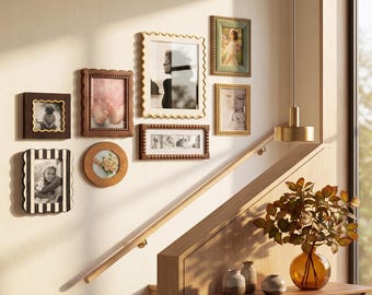 May include: A gallery wall arrangement featuring seven assorted picture frames in various shapes, sizes, and finishes, including dark wood, light wood, gold, and black and white striped designs, displaying various photographs on a light wall.