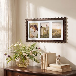 May include: A rectangular dark brown wooden picture frame with a scalloped edge design. The frame features three vertical openings with white matting, each displaying a photograph of a family in an outdoor setting during the golden hour.