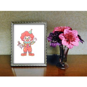May include: A framed picture of a cartoon clown with red hair, a party hat, and colourful clothing. The clown is holding a wand and waving. A vase of pink and purple flowers sits to the right of the frame on a wooden surface.