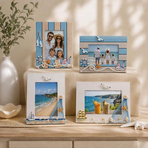 Könnte beinhalten: Vier rechteckige Bilderrahmen mit nautischen Motiven. Zwei Rahmen haben blau-beige Holzlatten mit Möwen, Segelbooten, Steuerrädern und Seilen. Zwei weiße Rahmen sind mit Muscheln, Seesternen und Fischernetzen verziert.