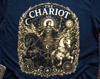 Op de afbeelding: Een marineblauw t-shirt met korte mouwen en een gedetailleerde grafische print van de tarotkaart De Zegewagen. Het ontwerp toont een figuur in een wagen getrokken door twee paarden, omringd door goudkleurig filigraan, sterren en de tekst THE CHARIOT VII.