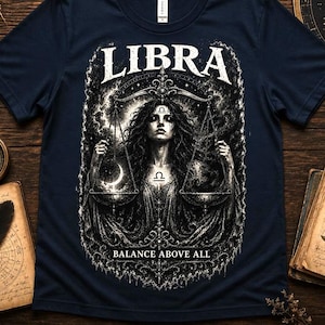 Könnte beinhalten: Ein dunkelblaues T-Shirt mit einem weißen Grafikdruck einer Person, die eine Waage hält. Der Text LIBRA steht über der Figur und der Text BALANCE ABOVE ALL darunter. Das Design enthält verschiedene himmlische und astrologische Motive.