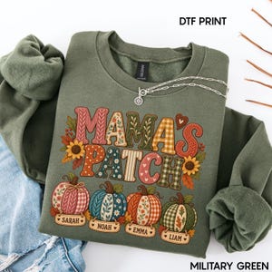 May include: A military green crewneck sweatshirt featuring a DTF print with the text MAMA'S PATCH in colorful patterned letters. Below the text are four pumpkins with hanging name tags labeled Sarah, Noah, Emma, and Liam, decorated with sunflowers.