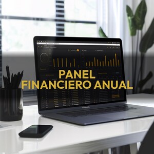 May include: A laptop displaying a financial dashboard with the text "PANEL FINANCIERO ANUAL" in gold. The laptop is on a white desk with a black smartphone and a black pencil holder. A window and a plant are in the background.
