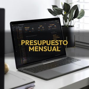 May include: A gray laptop displaying financial data with the text "PRESUPUESTO MENSUAL" in gold. The laptop is on a white desk with a notebook and a plant in a black pot in the background.