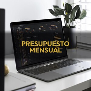 May include: A gray laptop displaying financial data with the text "PRESUPUESTO MENSUAL" in gold. The laptop is on a white desk with a notebook and a plant in a black pot in the background.