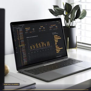 Puede incluir: Un port&aacute;til que muestra un panel financiero con gr&aacute;ficos y datos. La pantalla muestra el texto "Monthly Master Budget" y "Google Sheets + Excel + Automated". El port&aacute;til est&aacute; sobre una superficie blanca con una planta en el fondo. En la esquina superior izquierda pone "FINANCIAL OS #02".