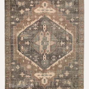 May include: A rectangular area rug featuring a large central diamond medallion in shades of charcoal gray, muted brown, and soft sage green. The rug displays intricate geometric and floral motifs throughout, with the text EliteRugsColN in the corner.