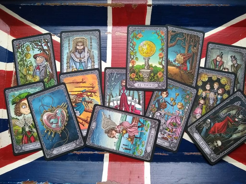 May include: A spread of tarot cards on a red, white, and blue patterned surface. The cards feature dark gray borders with intricate designs and colorful illustrations. The cards include "Page of Pentacles", "Five of Wands", "Ace of Pentacles", "Ten of Cups", "Temperance", "The Devil", "The Fool", and "Three of Swords".