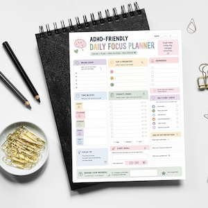 Könnte beinhalten: Ein Tagesplaner-Blatt mit dem Titel ADHD-FRIENDLY DAILY FOCUS PLANNER mit Abschnitten für Brain Dump, Top-Prioritäten, Erinnerungen, Zeitblöcke, Aufgaben, Selbstfürsorge und Tagesreflexion, inklusive einer rosa Gehirn-Illustration.