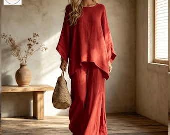 May include: A rust-colored linen two-piece outfit, consisting of a loose-fitting top and wide-leg pants. The top has a round neckline and batwing sleeves. A woven bag is carried. The outfit is suitable for casual wear.
