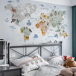 Peut inclure: Un grand autocollant mural représentant une carte du monde avec des continents aux tons pastel et divers animaux de dessin animé, dont un élan, un chameau, une girafe et un panda. La carte inclut des noms de continents et d'océans.