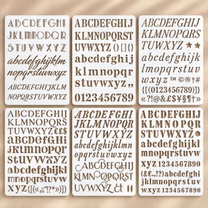 Può includere: Sei stencil rettangolari in plastica bianca con vari set tipografici di colore marrone. Ogni stencil mostra una collezione unica di lettere maiuscole e minuscole, numeri e simboli, incluse font serif, sans-serif e corsive.