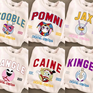 May include: Six white crewneck sweatshirts featuring The Amazing Digital Circus character graphics. Each shirt displays a character name in varsity-style lettering, a circular character illustration, the text EST. 2023, and The Amazing Digital Circus logo.