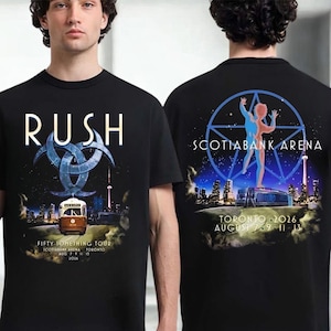 May include: A black t-shirt featuring a Rush Fifty-Something Tour graphic. The front displays a streetcar, city skyline, and the text 'RUSH'. The back shows a pentagram, a human figure, the Scotiabank Arena, and 'TORONTO AUGUST 7 9 11 13 2026'.