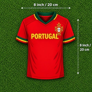 K&ouml;nnte beinhalten: Ein rotes Kurzarmtrikot mit V-Ausschnitt, gelbem Schriftzug PORTUGAL und einem Wappen auf der Brust. Die &Auml;rmel haben gr&uuml;ne und gelbe Abschl&uuml;sse. Das Trikot misst 20 cm in der Breite und 20 cm in der H&ouml;he, wie durch die Markierungen angezeigt.
