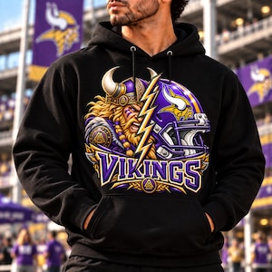 May include: A black hooded sweatshirt featuring a graphic print of a Viking warrior with a horned helmet and a purple football helmet, separated by a yellow lightning bolt. The word VIKINGS is printed in purple and yellow lettering below.
