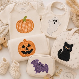 May include: A cream-coloured baby bodysuit with a gingham pumpkin, a bib with a white ghost, a folded blanket with a jack-o'-lantern, a zipped pouch with a purple bat, and a small bag with a black cat. Includes a pair of cream knit booties.