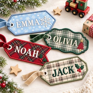 May include: Four personalized fabric gift tags with velvet ribbons. One light blue tag with white snowflakes and the name EMMA. One green plaid tag with the name OLIVIA and a tree. One red plaid tag with the name NOAH and holly. One beige plaid tag with the name JACK and holly.