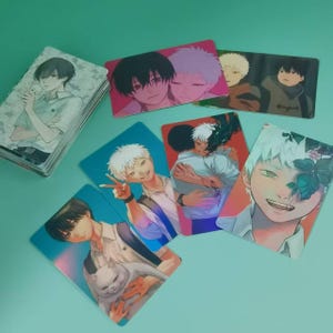 Könnte beinhalten: Eine Sammlung rechteckiger Sammelkarten mit Anime-Illustrationen von Charakteren mit verschiedenen Haarfarben wie Schwarz, Weiß und Blond. Die Karten zeigen Szenen von Charakteren, die interagieren, sich umarmen und eine Katze halten.