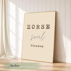 Könnte beinhalten: Gerahmter Kunstdruck mit den Worten "HORSE soul freedom" in einer Mischung aus Serifen- und Schreibschrift. Der Hintergrund ist hellbeige, und der Rahmen ist goldfarben. Der Druck lehnt an einer weißen Wand.